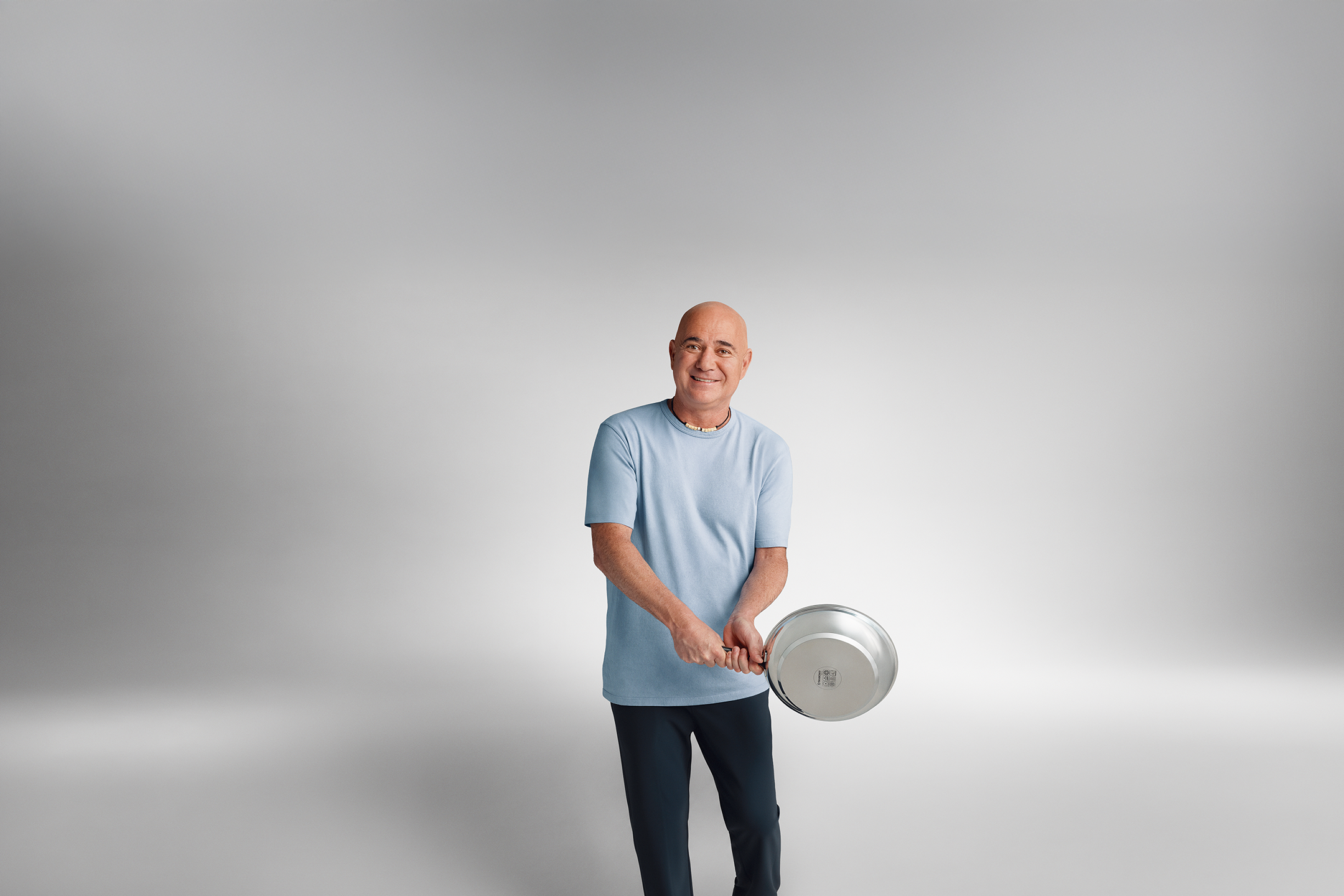 Andre Agassi kék pólóban egy serpenyőt tart a kezében.