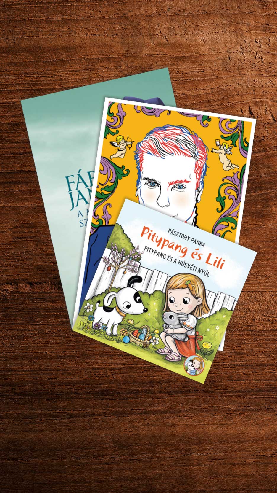 Három könyv, köztük egy gyermekkönyv Pitypang és Lili címmel, fa felületen.