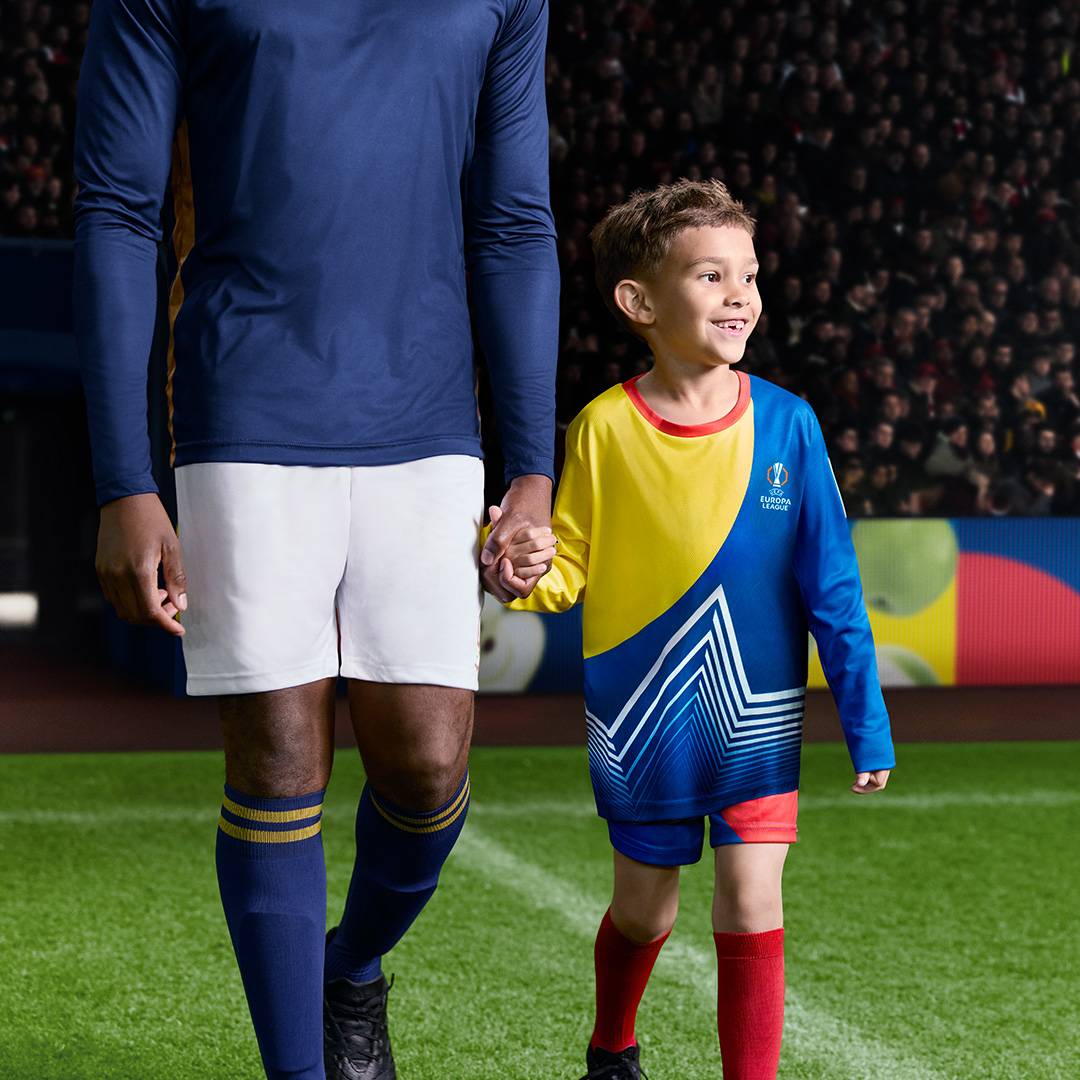 Felnőtt és gyermek focista a pályán, a gyermek Europa League mezt visel.