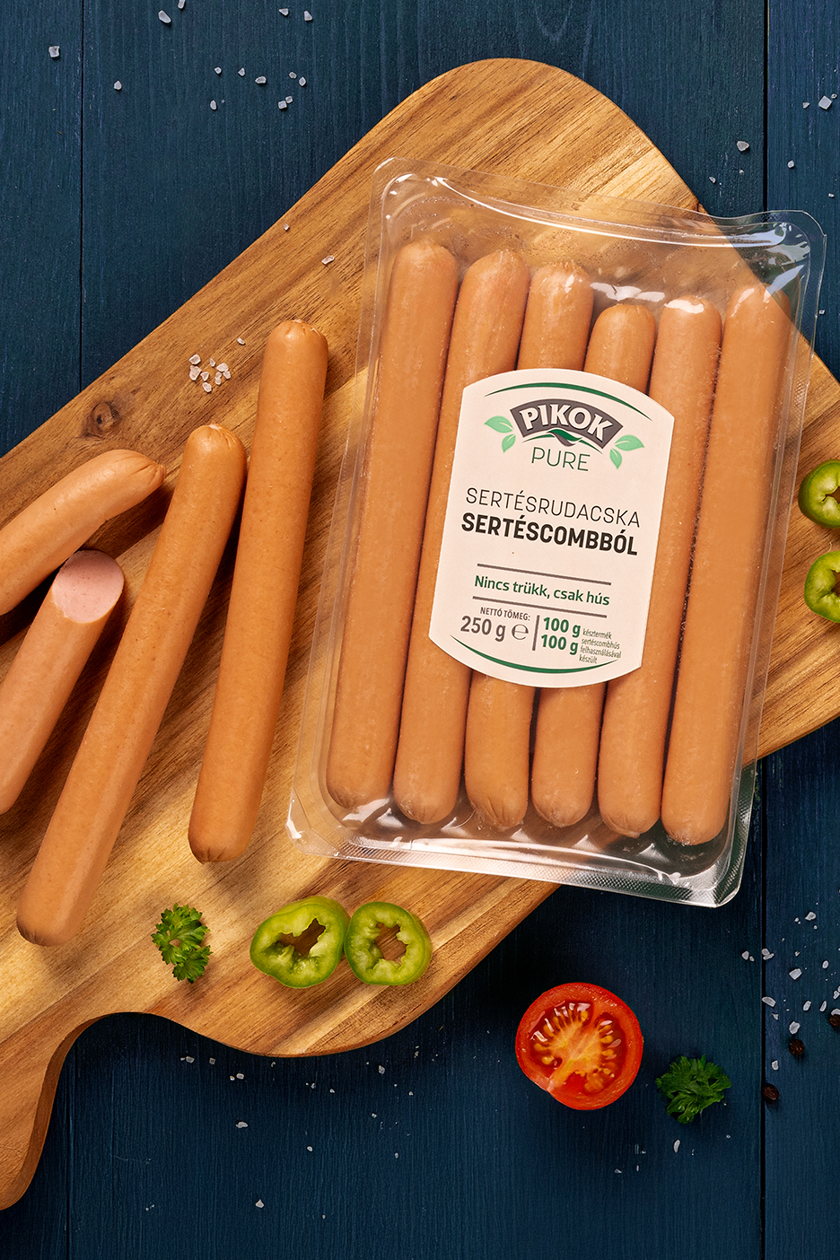 Pikok Pure sertésrudacskák csomagolásban és vágódeszkán, zöldségekkel.