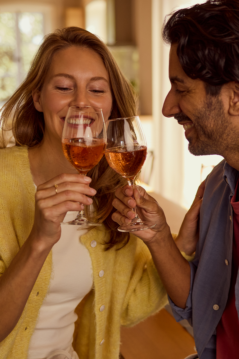 Pezsgővel koccintó pár, a nő sárga kardigánt visel.