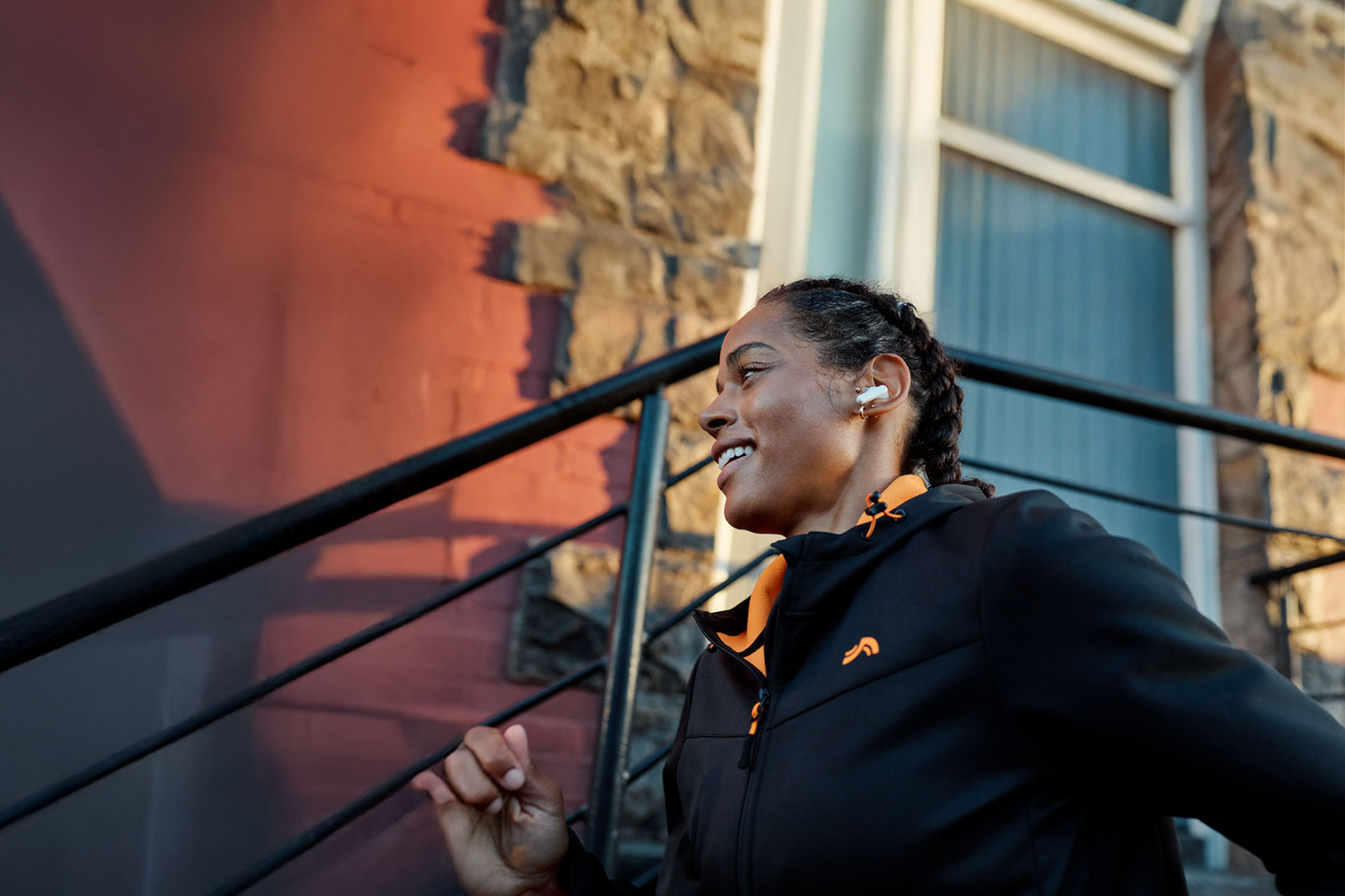 Nő fut fülhallgatóval, dzsekit visel.